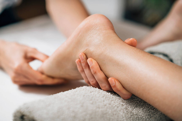 Аюрведический массаж ног. Руки практикующего аюрведы массируют женскую ногу  - Фото, изображение