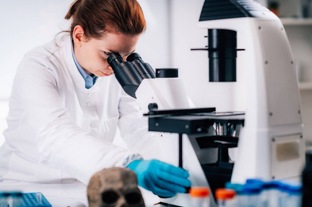 Αρχαία ανάλυση DNA. Γυναίκα επιστήμονας κρατώντας μικρο σωλήνα με δείγμα στο αρχαίο εργαστήριο DNA. - Φωτογραφία, εικόνα
