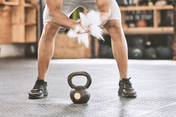 Trainer dusting hands before weight training. Strong athlete using hand powder before lifting a kettlebell. Strong athlete using chalk before lifting heavy weights in the gym. Powder before weights. - 写真・画像