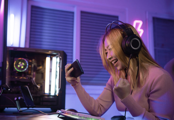 A Professional female pro gamer play online mobile games cyber sport and esport winner emotion. Young woman in tournament match worldwide in room colorful neon lights. - Foto, afbeelding
