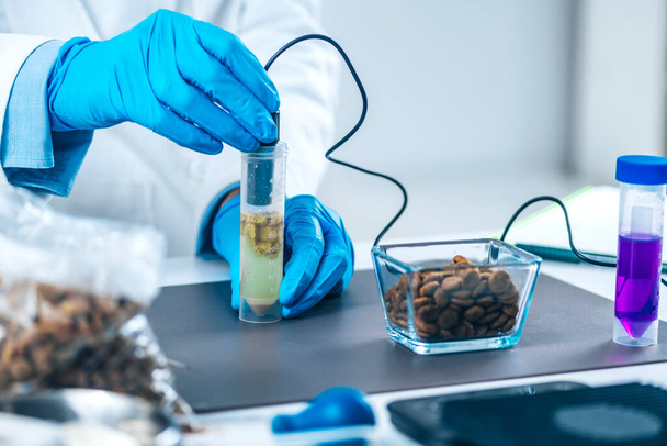 Cientista que mede PH de alimentos para animais de estimação dissolvidos em tubo de amostra com medidor de PH. - Foto, Imagem