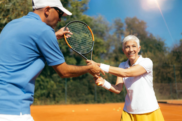 Senior Woman Training with Tennis Instructor on a Clay Court - Fotó, kép
