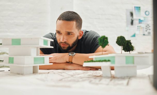 建築模型を中心とした建築家。若いビジネスマンはビルモデルを考えている。3Dビルディングモデルに取り組むハンサムなエンジニア。3Dモデルに取り組むエンジニア. - 写真・画像