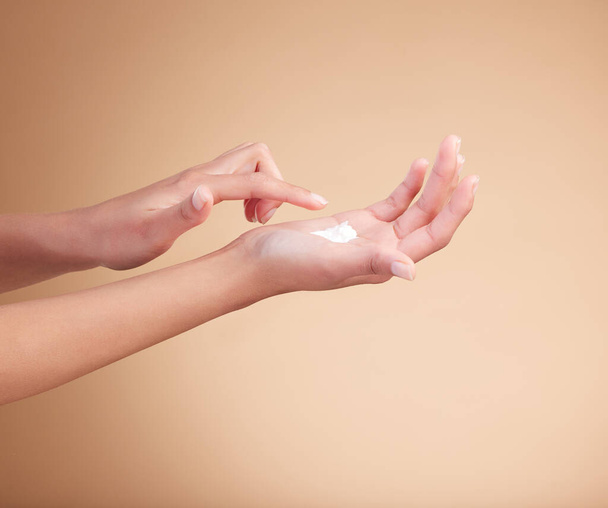 Hands, manicure and palm with lotion, creme or cream by female model with cosmetic care, skincare or self care. Polish, moisturizer and natural nails or skin glow isolated in brown studio background. - Φωτογραφία, εικόνα