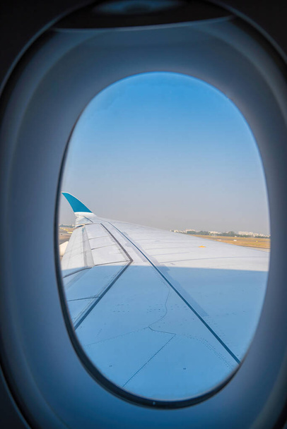 Widok z okna samolotu na lotnisku Tan Son Nhat. Niebieskie niebo i puszyste białe chmury z widokiem na okno samolotu, silnik odrzutowy na skrzydle. Rezerwacja biletów lotniczych - miejsce przy oknie samolotu. Skupienie selektywne - Zdjęcie, obraz