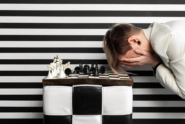An angry and upset woman gesticulates with her hands while sitting at a chessboard. Emotional defeat in the game. - Φωτογραφία, εικόνα