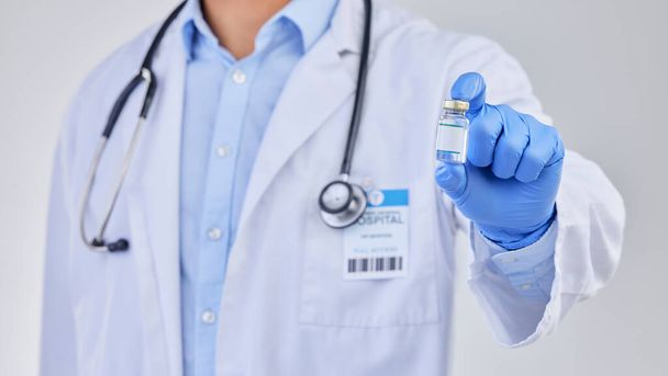 Vaccine vial, doctor and hands in studio for safety, healthcare and pharmaceutical medicine. Closeup, vaccination and bottle for virus immunity, medical antibiotics and wellness drugs on background. - 写真・画像