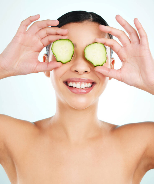 The perfect eye treatment. Studio shot of an attractive young woman posing with cucumber slices against a light background - Foto, afbeelding