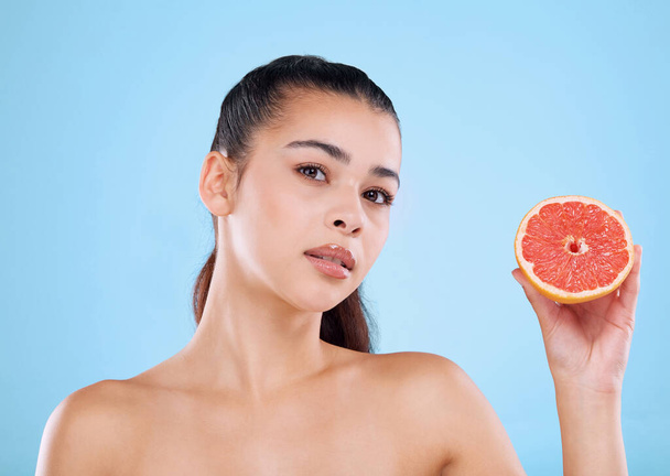 Heb je grapefruit geprobeerd? Studio portret van een aantrekkelijke jonge vrouw poseren met een halve grapefruit tegen een blauwe achtergrond - Foto, afbeelding