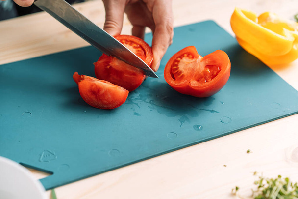 Mujer cortando tomate para ensalada de verduras con microgreens. - Foto, imagen
