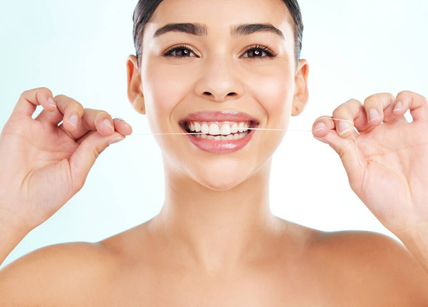Bei der Zahnhygiene gibt es keine Abkürzungen. Studioporträt einer attraktiven jungen Frau mit Zahnseide vor hellem Hintergrund - Foto, Bild