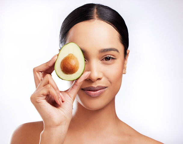 The secret ingredient for soft and supple skin. Studio portrait of a beautiful young woman posing with an avocado against a white background - Photo, image