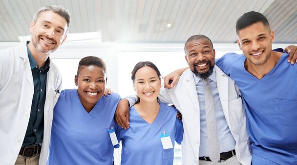 Опираясь на свои навыки, чтобы поставить обоснованный диагноз. веселая группа врачей, стоящих с обнимающимися руками в больнице в течение дня - Фото, изображение