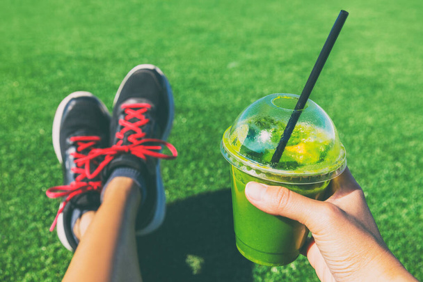 Green smoothie detox cleanse runner girl drinking plastic cup take-out food. Healthy eating weight loss concept. - 写真・画像