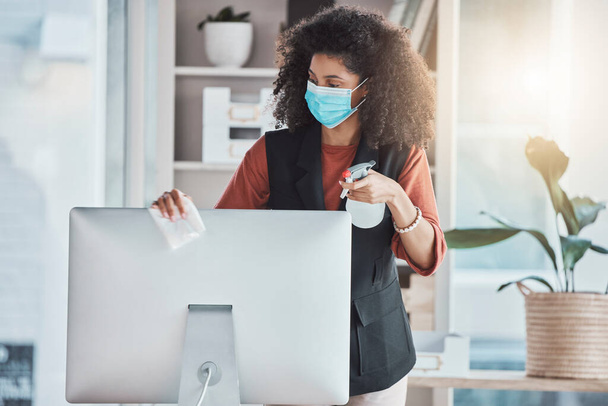 Woman, covid and spray for cleaning computer with face mask, workplace safety and liquid for healthcare. Professional cleaner, desktop pc and clean to stop virus in office with bacteria risk at job. - Photo, Image