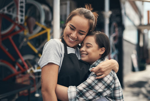 The sister I always wanted. two young female colleagues sharing a hug outside a bicycle repair shop - Foto, afbeelding