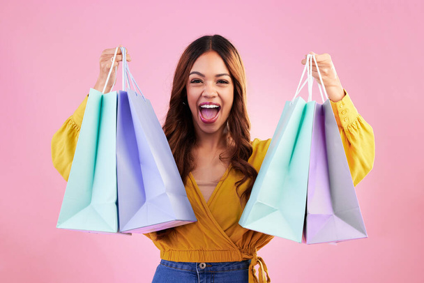 Woman excited about shopping purchase, paper bag and retail, happy in portrait on pink background. Cheers, excitement about discount and promotion, fashion product and female with smile in studio. - Photo, Image