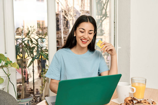 Portret van een vrolijke blanke vrouw online winkelen met behulp van een laptop thuis - Foto, afbeelding