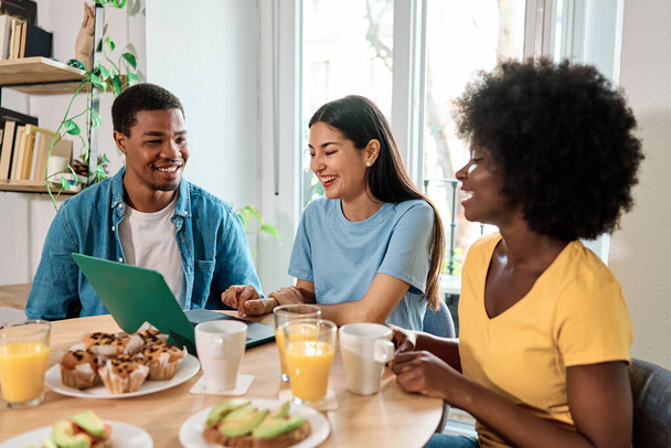 Multiethnische Gruppe von Freunden mit Laptop beim Frühstück zu Hause - Foto, Bild