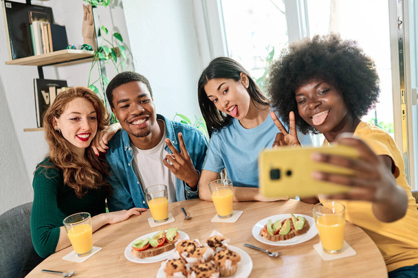 Multiethnische Gruppe von Freunden grimmig und gestikulierend, während sie Spaß beim gemeinsamen Selfie zu Hause haben - Foto, Bild