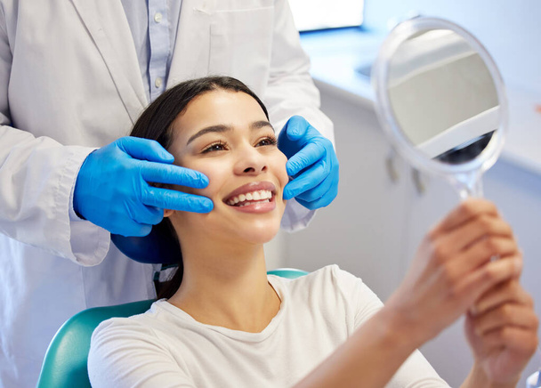 Recuperé mi sonrisa. una joven admirando sus dientes después de hacerse un procedimiento dental - Foto, imagen