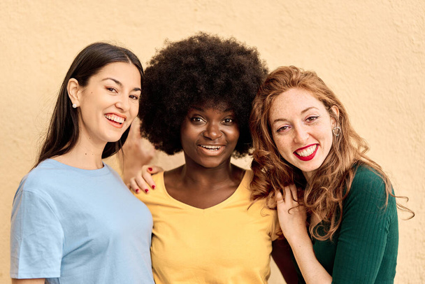Retrato de estudio de tres amigas multirraciales sonriendo a la cámara - Foto, imagen