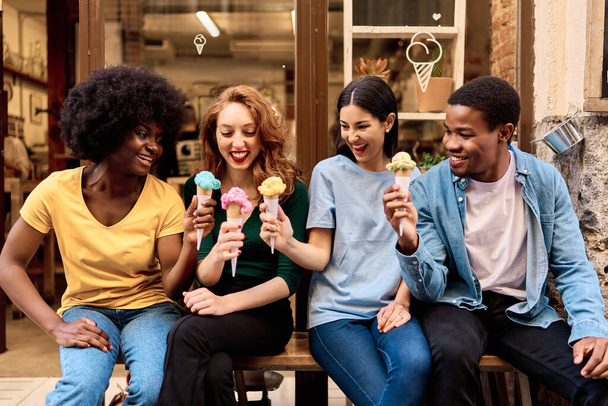 Frontális kilátás többnemzetiségű baráti társaság ünneplő evés közben fagylalt szabadban - Fotó, kép