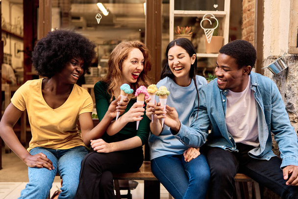 Frontális kilátás többnemzetiségű baráti társaság ünneplő pohárköszöntő közben fagylalt szabadban - Fotó, kép