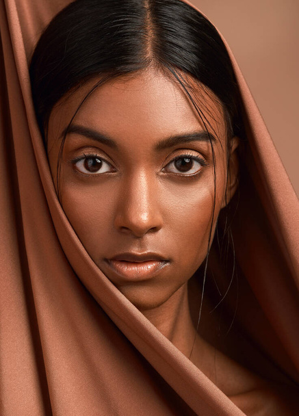 Who wouldnt stand inside her sun. Portrait of an attractive young woman wearing a head scarf against a brown background - Photo, Image