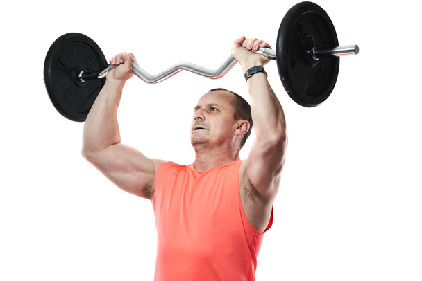 Mature athletic man in pink tee doing fitness workout with barbell and weights, isolated on white background - Φωτογραφία, εικόνα