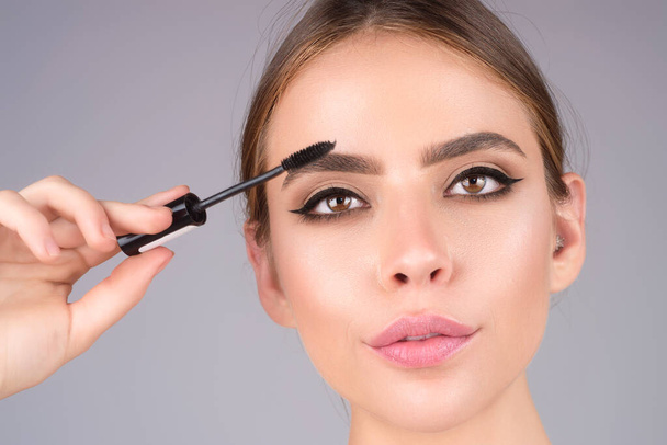 Female model shaping brown eyebrows. Woman eye with beautiful eyebrows. Perfect shaped brow, eyelashes with brow gel brush. Paint eyebrows - 写真・画像