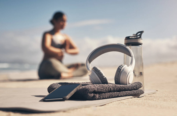 Csak néhány dolog van, amire szükséged van egy jó edzés. mobiltelefon, fejhallgató, törölköző és vizes palack a strandon - Fotó, kép