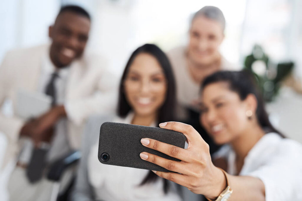 More than colleagues. a group of diverse businesspeople taking selfies while gathered in their office - 写真・画像