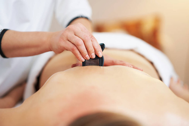 Donna che fa un massaggio gua sha nel salone. Foto di alta qualità - Foto, immagini