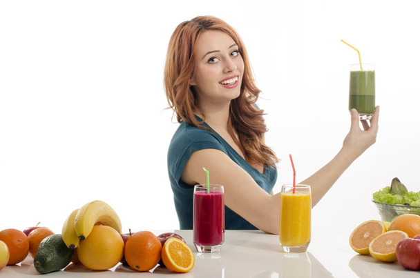 Happy woman having a table full of organic food,juices and smoothie. Cheerful young woman eating healthy salad and fruits. Isolated on white. - Photo, Image