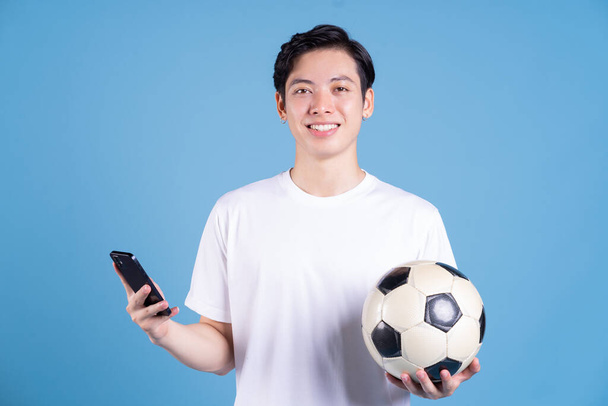 Νεαρός Ασιάτης άνδρας κρατώντας μπάλα στο παρασκήνιο - Φωτογραφία, εικόνα