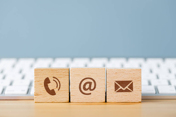 Communication icons on wooden cube blocks and in front of a keyboard. Contact us or e-mail marketing concept  - Фото, зображення