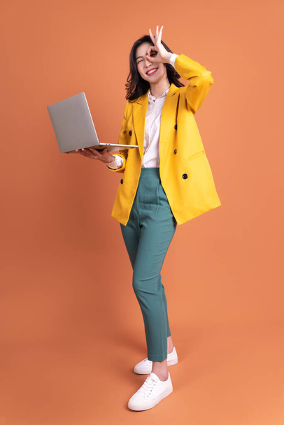 Full length photo of young Asian woman using laptop on background - Фото, изображение