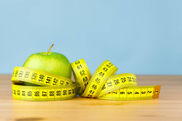 A measuring tape wrapped around a green apple. Healthy eating and diet concept.   - Photo, Image