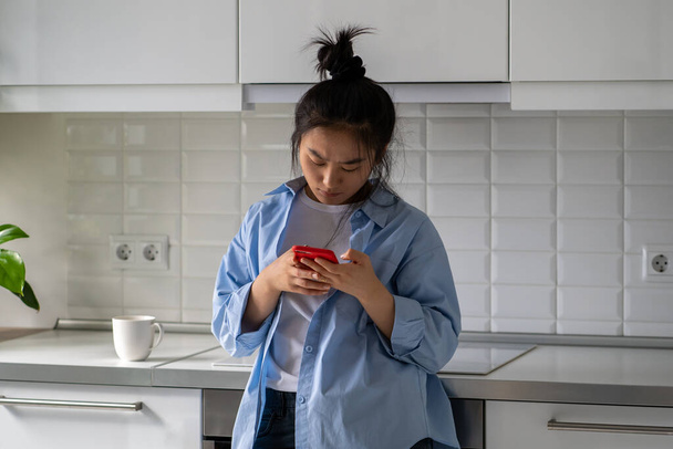 Szemöldökráncolás bosszús ázsiai fiatal nő tartja okostelefon kap üzenetet vagy e-mailt a gyenge információkat. Zavarodott kínai lány néz a mobilon lásd fontos hívás nem fogadott, rossz hír a képernyőn, bosszantotta spam - Fotó, kép