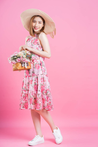 Foto de una joven asiática con vestido de flores sobre fondo rosa - Foto, Imagen