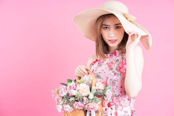 ピンクの背景に花のドレスを着た若いアジアの女の子の写真 - 写真・画像