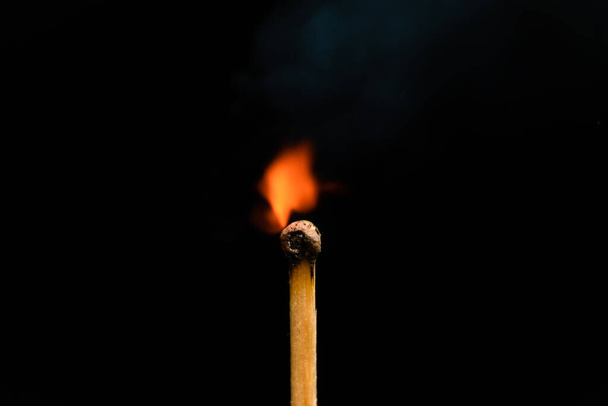 Igniting match on a black background, macro photography. Newly lit match with smoke on a black background. Concept of beginning, leadership, strengthening the spirit - Photo, Image