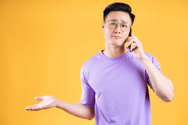 Kuva nuoresta aasialaisesta miehestä älypuhelimella taustalla - Valokuva, kuva