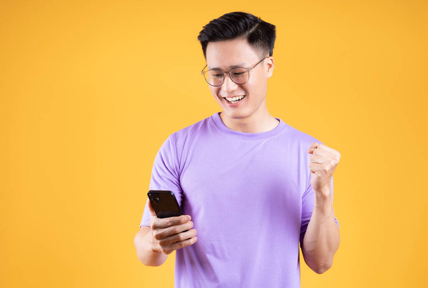 スマートフォンを背景にした若いアジア人男性のイメージ - 写真・画像