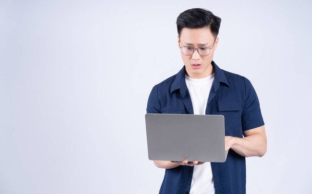 Νεαρός Ασιάτης που χρησιμοποιεί φορητό υπολογιστή σε λευκό φόντο - Φωτογραφία, εικόνα