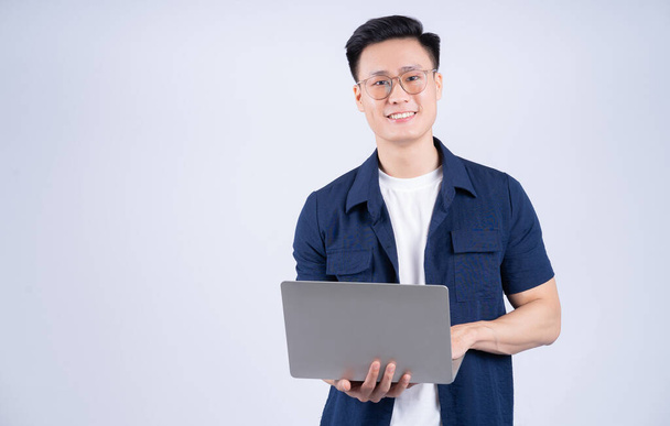 Young Asian man using laptop on white background - Φωτογραφία, εικόνα