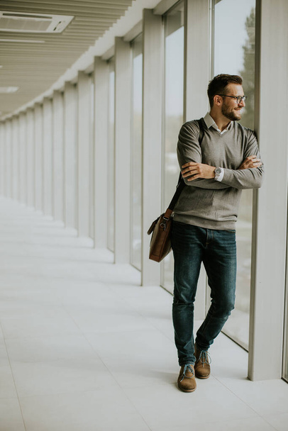Guapo joven empresario moderno de pie en el pasillo de la oficina - Foto, Imagen
