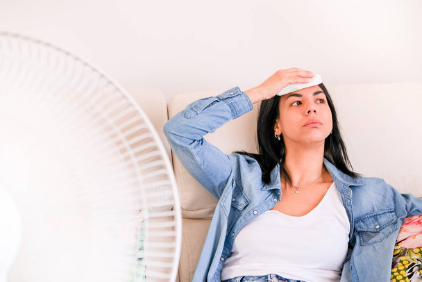 Vrouw die last heeft van zomerhitte probeert koel en comfortabel te blijven tijdens hittegolf - Foto, afbeelding