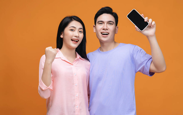 背景にスマートフォンを使う若いアジアのカップル - 写真・画像
